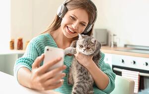 Woman holding cat takes selfie with smartphone